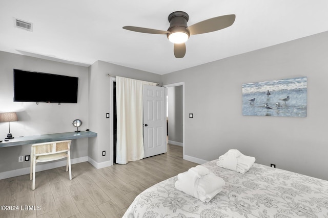 bedroom with ceiling fan, built in desk, and light hardwood / wood-style floors