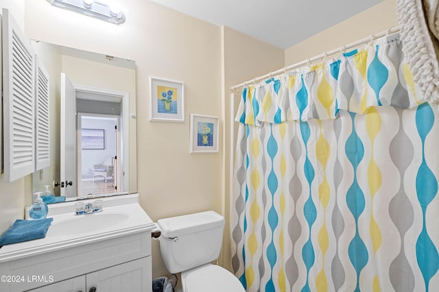 bathroom with walk in shower, vanity, and toilet