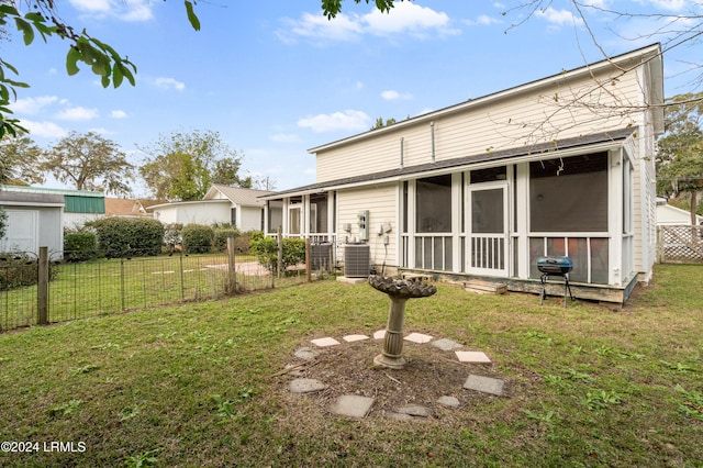 rear view of house with a sunroom, central AC, and a lawn