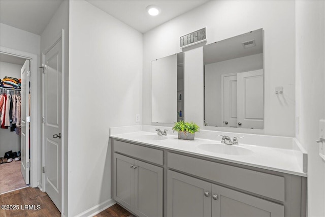 full bath with double vanity, visible vents, wood finished floors, and a sink