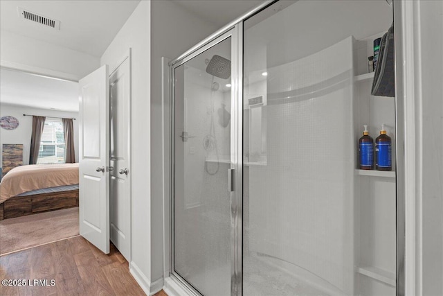 ensuite bathroom featuring visible vents, wood finished floors, connected bathroom, and a shower stall