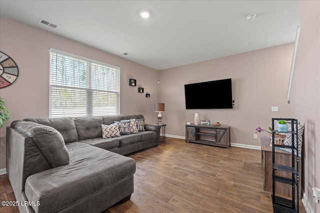 living room featuring visible vents, baseboards, and wood finished floors