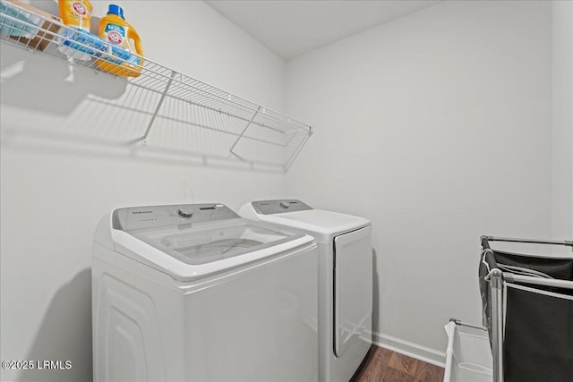 clothes washing area featuring laundry area, washer and dryer, baseboards, and dark wood-style flooring