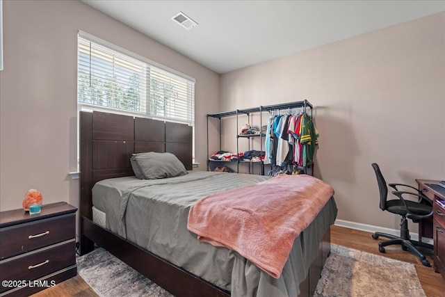 bedroom featuring visible vents, baseboards, and wood finished floors