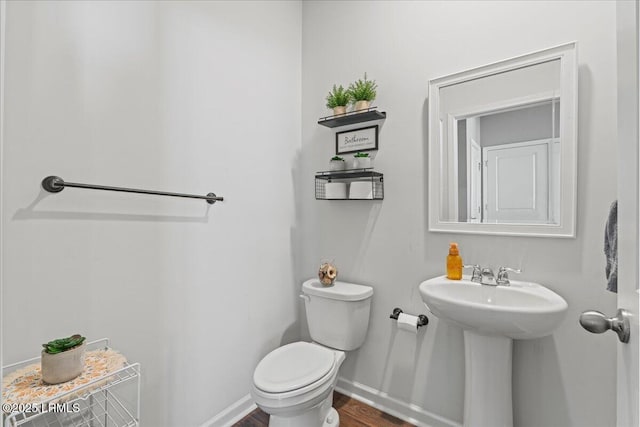 bathroom featuring toilet, baseboards, and a sink