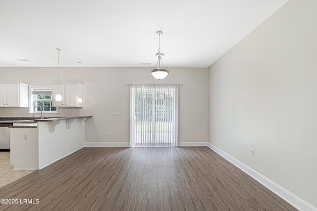 4 Applemint Ln, Beaufort, SC 29906 - kitchen featuring dark wood-style flooring, a kitchen bar, white cabinets, and hanging light fixtures