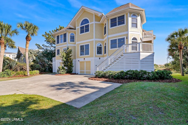 view of front of home with a garage, a front lawn, and a balcony