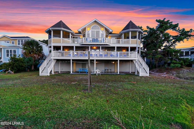 back house at dusk featuring a deck and a lawn