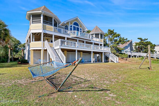 rear view of house with a yard, a deck, and a sunroom