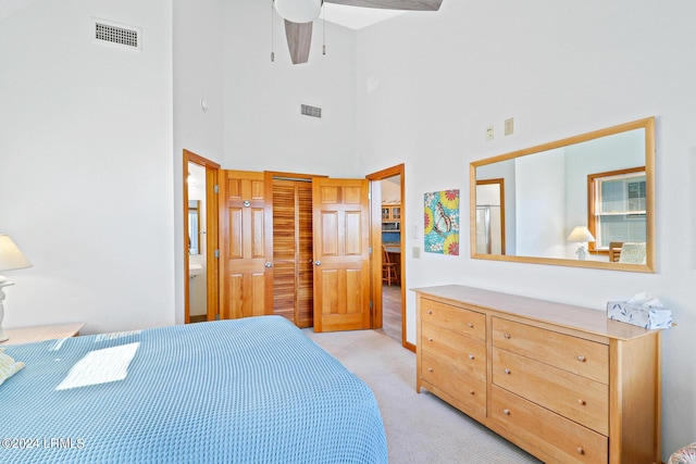 carpeted bedroom with a closet, ceiling fan, and a high ceiling