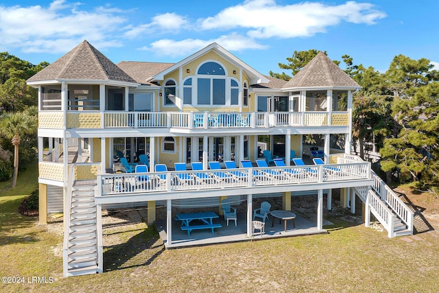 rear view of property with a sunroom, a lawn, a deck, and a patio area