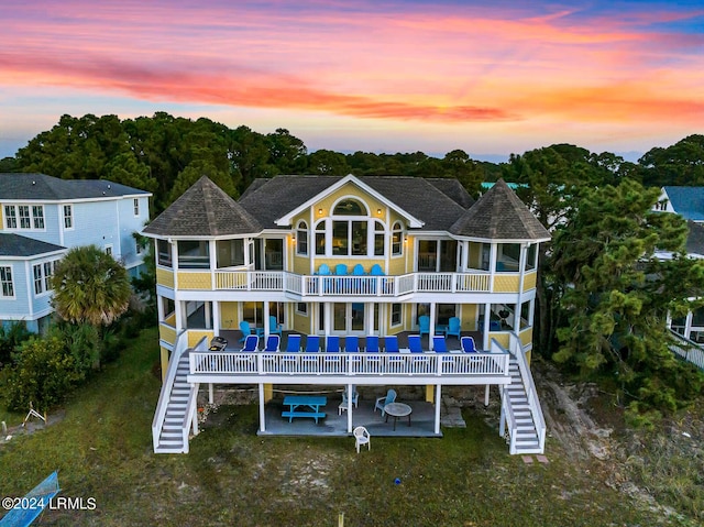 back house at dusk with a patio area and a balcony