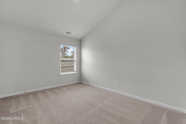 unfurnished room featuring light colored carpet and lofted ceiling