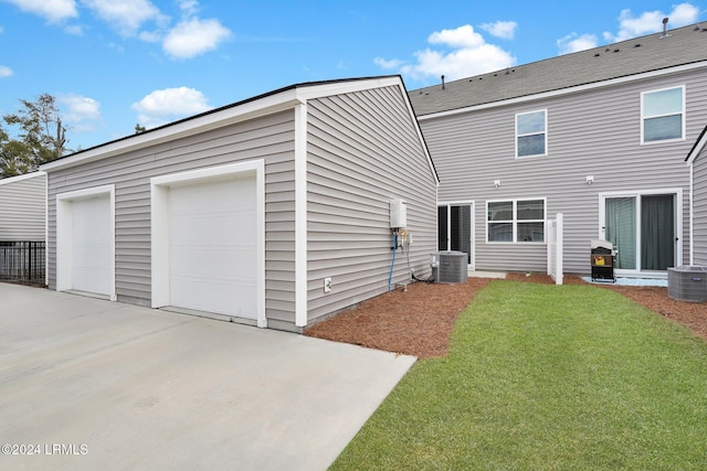 rear view of property with a yard, a garage, and central AC unit