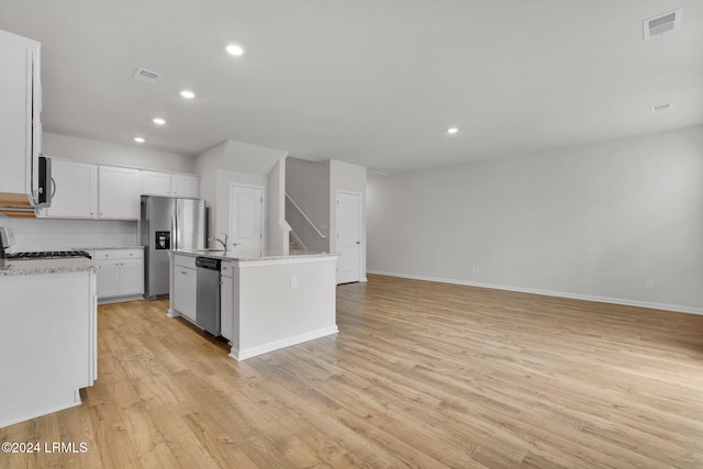 kitchen featuring white cabinetry, stainless steel appliances, tasteful backsplash, light hardwood / wood-style floors, and an island with sink