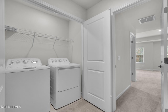 laundry area with separate washer and dryer and light carpet