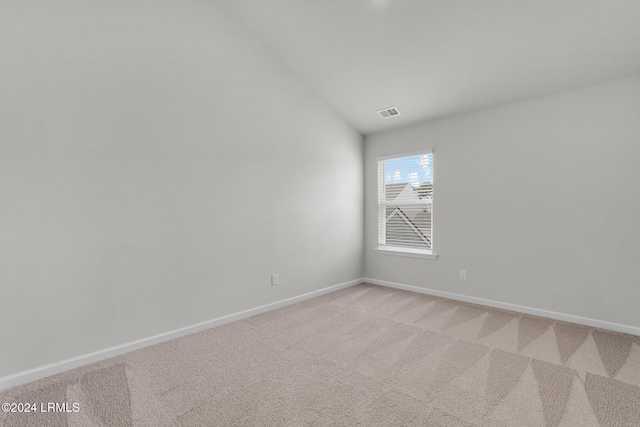 spare room featuring vaulted ceiling and light carpet