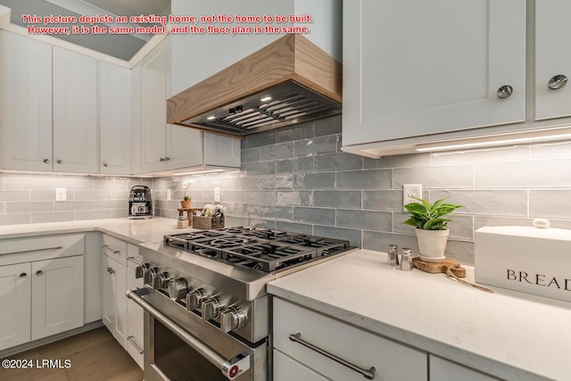 kitchen featuring high end stainless steel range oven, premium range hood, tasteful backsplash, and white cabinets