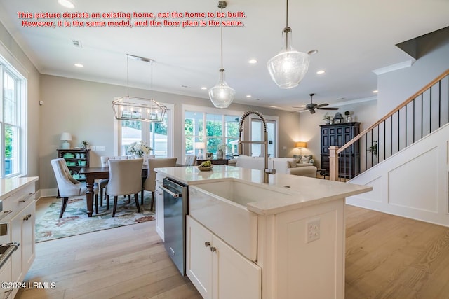 kitchen with pendant lighting, sink, ornamental molding, a center island with sink, and light wood-type flooring