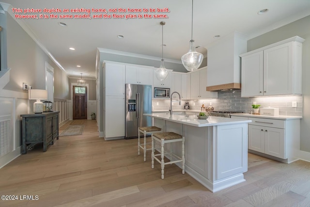 kitchen featuring a kitchen island with sink, custom exhaust hood, stainless steel appliances, and white cabinets