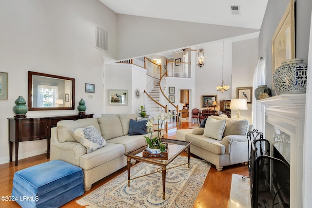 living room featuring high vaulted ceiling, an inviting chandelier, and light hardwood / wood-style floors