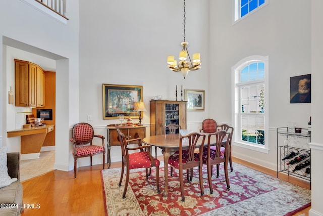 dining room featuring a towering ceiling, light hardwood / wood-style floors, and a chandelier