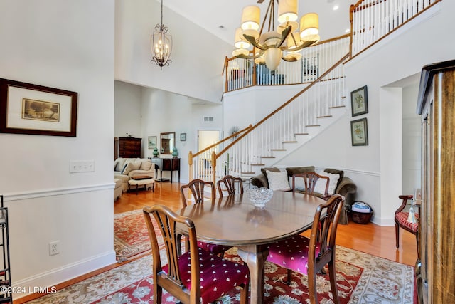 dining space featuring a high ceiling, hardwood / wood-style floors, and a notable chandelier