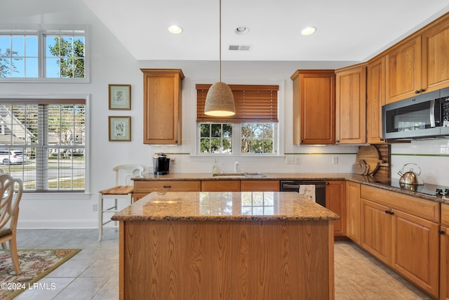 kitchen with pendant lighting, sink, a center island, light stone counters, and black appliances