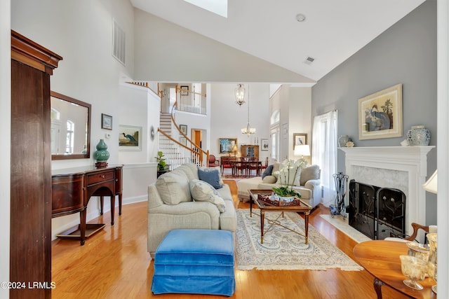 living room with high vaulted ceiling, a chandelier, and light hardwood / wood-style flooring