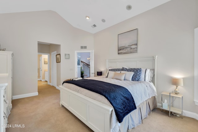 bedroom featuring lofted ceiling, ensuite bath, and light colored carpet