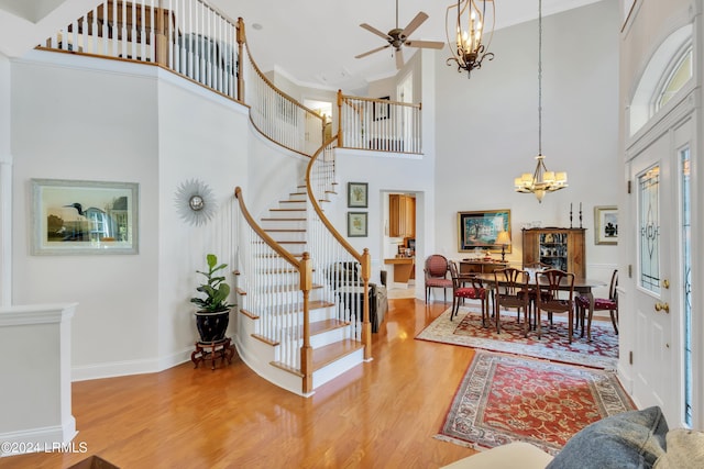 entrance foyer featuring a high ceiling, ceiling fan with notable chandelier, and hardwood / wood-style floors