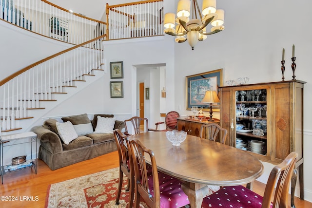 dining area featuring an inviting chandelier, wood-type flooring, and a high ceiling