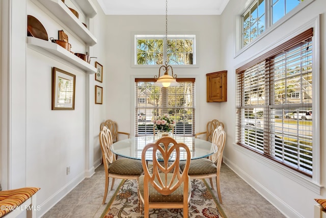 dining space with light tile patterned floors, crown molding, a healthy amount of sunlight, and a high ceiling