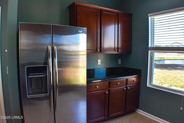 48 Pennyroyal Way, Beaufort, SC 29906 - kitchen with stainless steel refrigerator with ice dispenser, dark countertops, light tile patterned flooring, and reddish brown cabinets