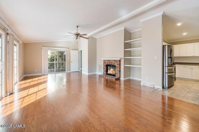 1 Wateree Ct, Beaufort, SC 29902 - unfurnished living room with ceiling fan, a brick fireplace, light wood-type flooring, built in features, and crown molding