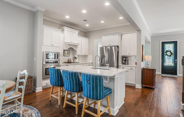 kitchen with dark hardwood / wood-style floors, white cabinetry, sink, stainless steel appliances, and a center island with sink