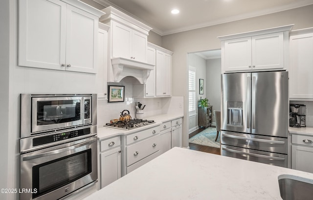 kitchen with ornamental molding, appliances with stainless steel finishes, decorative backsplash, and white cabinets