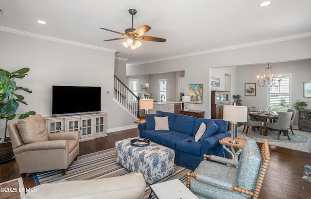 living room with crown molding, plenty of natural light, ceiling fan with notable chandelier, and dark hardwood / wood-style flooring