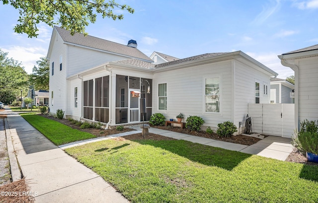 view of front of home featuring a sunroom and a front lawn