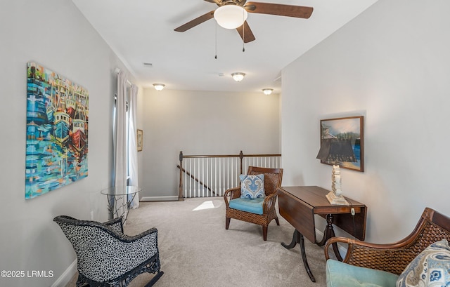 sitting room with ceiling fan and carpet