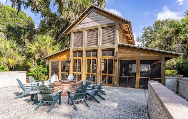 rear view of house with a patio, a sunroom, and a fire pit