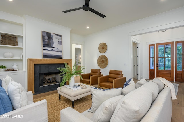 living room featuring crown molding, ceiling fan, built in features, and light wood-type flooring