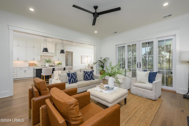 living room with ceiling fan, sink, and light hardwood / wood-style floors