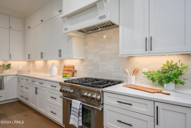 kitchen with white cabinetry, dark hardwood / wood-style floors, tasteful backsplash, high end stainless steel range, and custom range hood