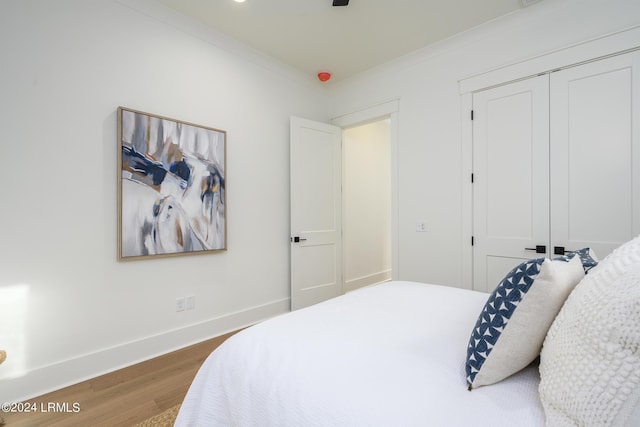 bedroom with crown molding, dark hardwood / wood-style floors, and a closet