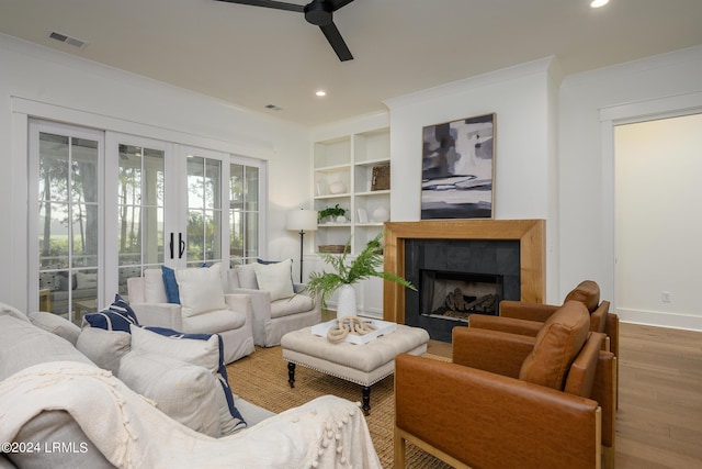 living room with ceiling fan, wood-type flooring, and ornamental molding