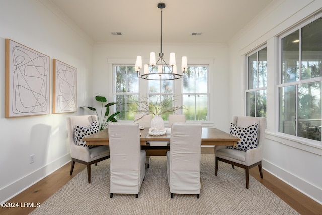 dining room with hardwood / wood-style flooring, crown molding, and a notable chandelier