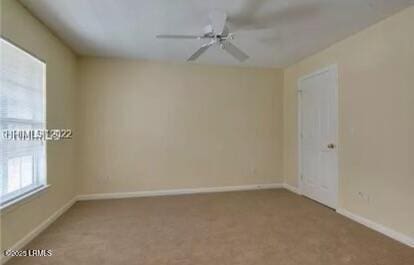 carpeted spare room with ceiling fan and baseboards