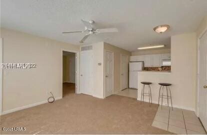 carpeted empty room with ceiling fan and baseboards