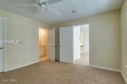 unfurnished bedroom with ensuite bathroom, ceiling fan, carpet, and baseboards